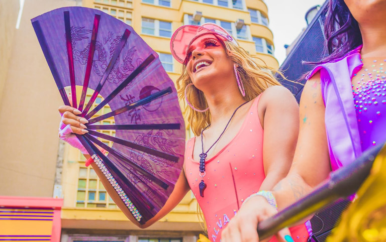Fotografia de uma drag com leque roxo no carnaval