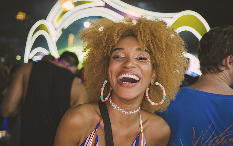 Fotografia colorida de uma pessoa negra sorrindo em uma festa