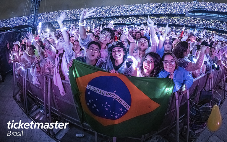 Fotografia colorida de público em show com a bandeira do Brasil por Ticketmaster Brasil - Foto por Live Nation Brasil - Iris Alves
