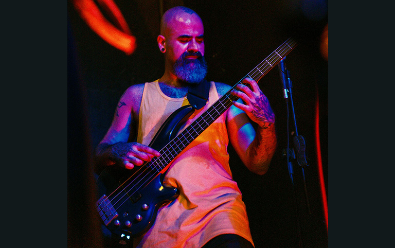 Fotografia colorida de Caio Bassetti tocando baixo - Anúncio como novo baixista da banda Crazyland 